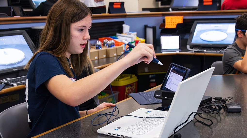 "Student using zSpace laptop and stylus in a classroom setting, engaging with interactive 3D learning tools. The image highlights the use of advanced educational technology in modern classrooms, showcasing zSpace's immersive learning environment.