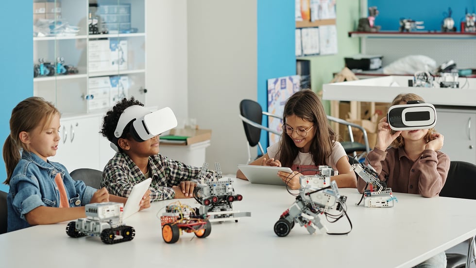 VR in Education showing students engaged in a STEM activity with robotics and virtual reality headsets in a classroom setting. They are interacting with various robotics kits, tablets, and VR headsets, highlighting hands-on learning and the integration of modern technology in education.