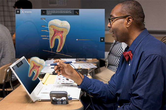 A man in a blue shirt and red bow tie uses zSpace's augmented reality technology to study a 3D model of a tooth on a laptop. The interactive display shows detailed anatomy of the tooth, including the enamel, dentin, and pulp chamber, enhancing dental education and training.