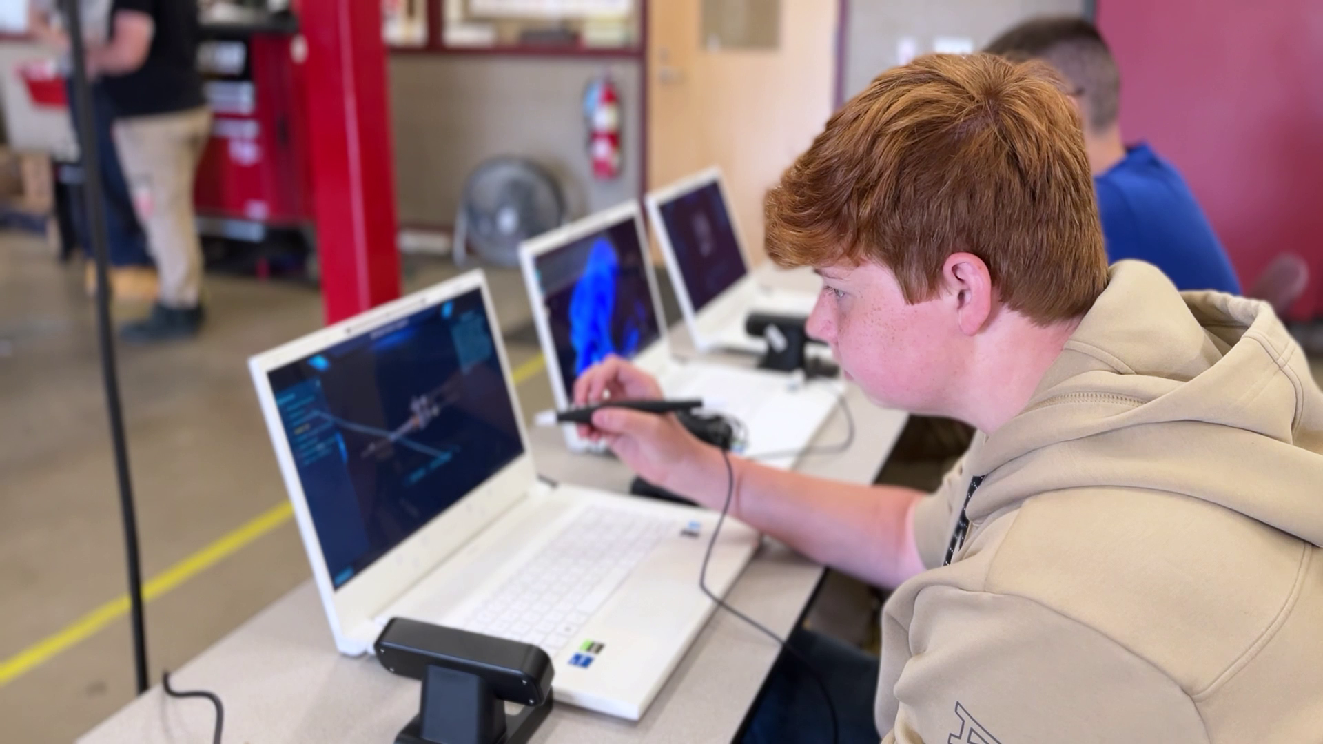 Students using laptops and styluses in a classroom setting, focusing on technical or engineering software.